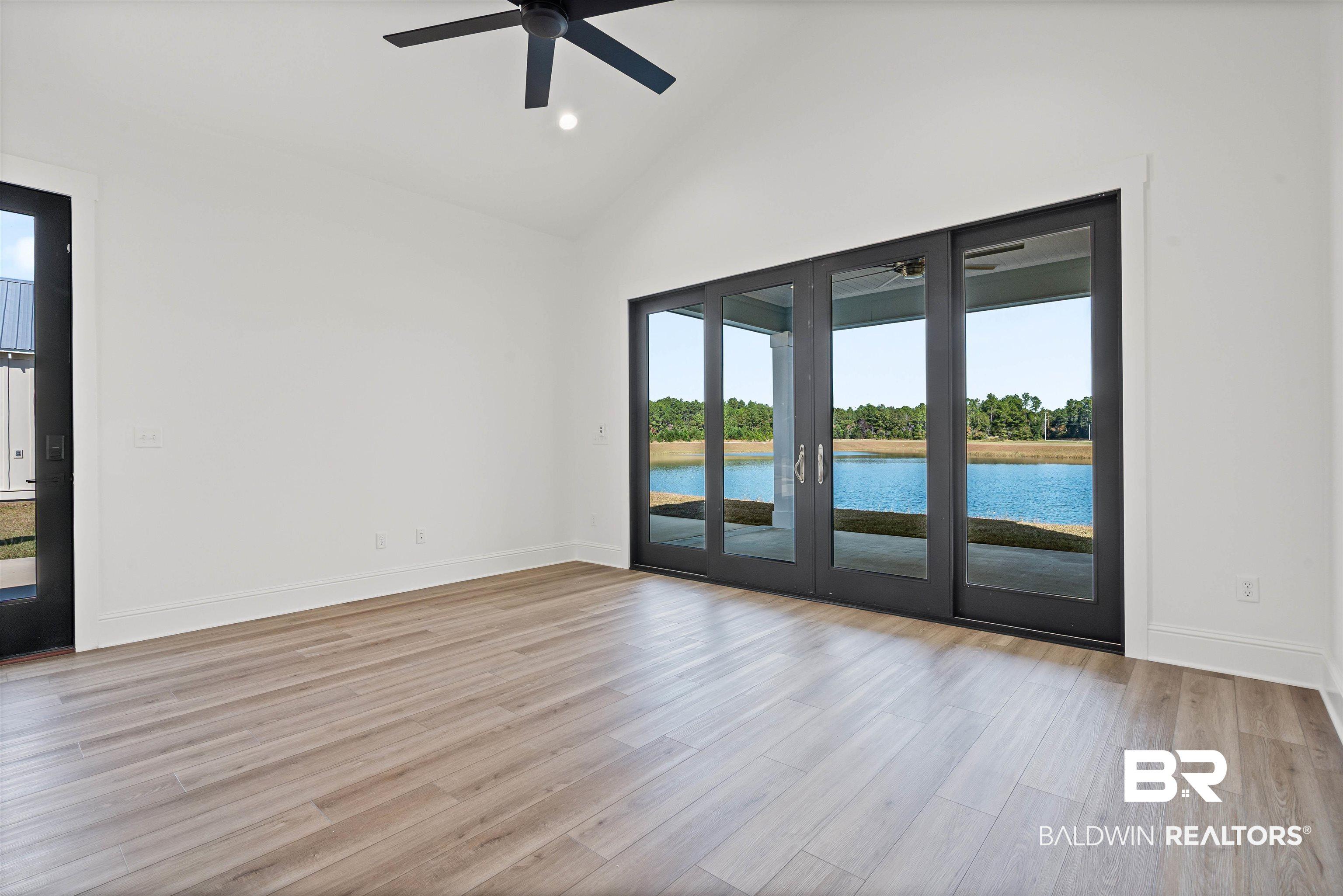 Image 2: Spare room featuring light wood-style flooring, high vaulted ceiling, a ceiling fan, recessed lighting, and a water view