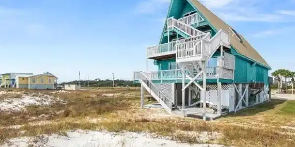 Image 2: View of front facade featuring a wooden deck and stairway