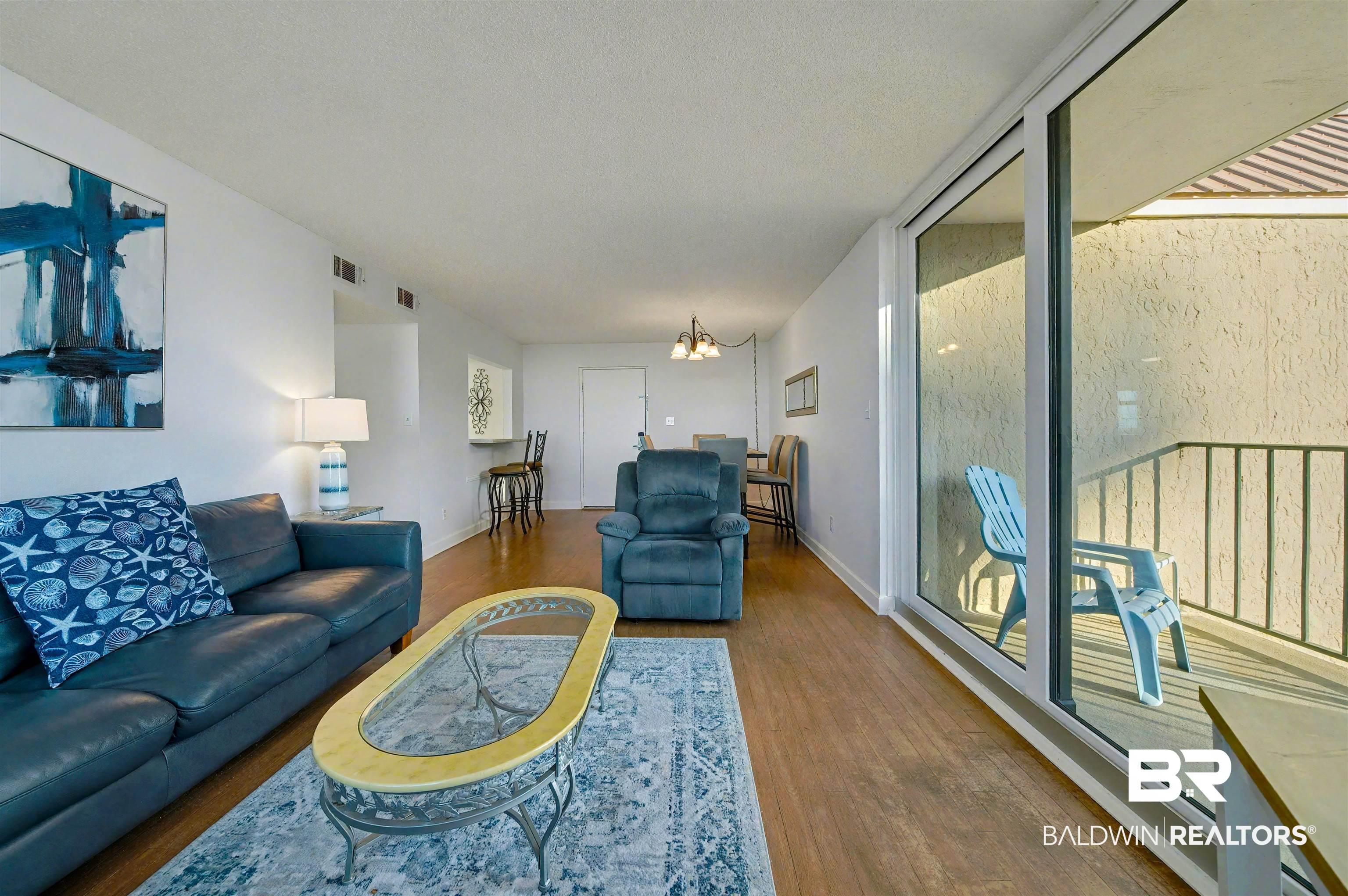 Image 4: Living area with wood finished floors and a chandelier