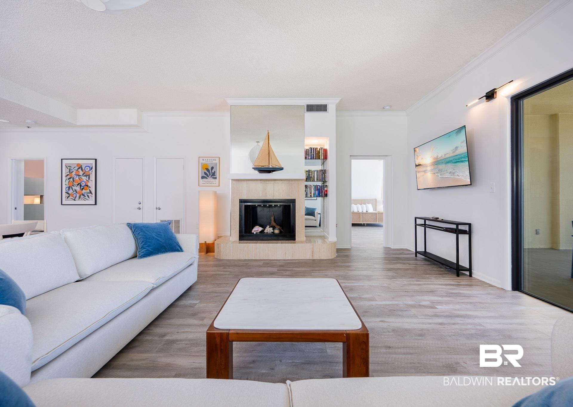 Image 4: Living area featuring light wood-finish flooring and a fireplace with a stone surround