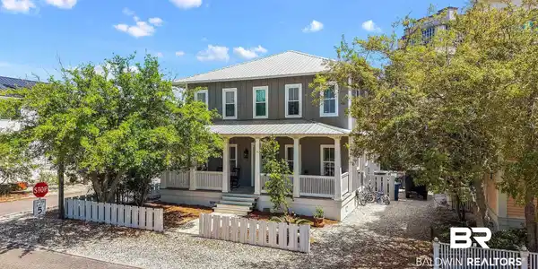 Image 4: Two-story residence featuring a gray exterior with white trim, a metal roof, and a covered front porch with white railings