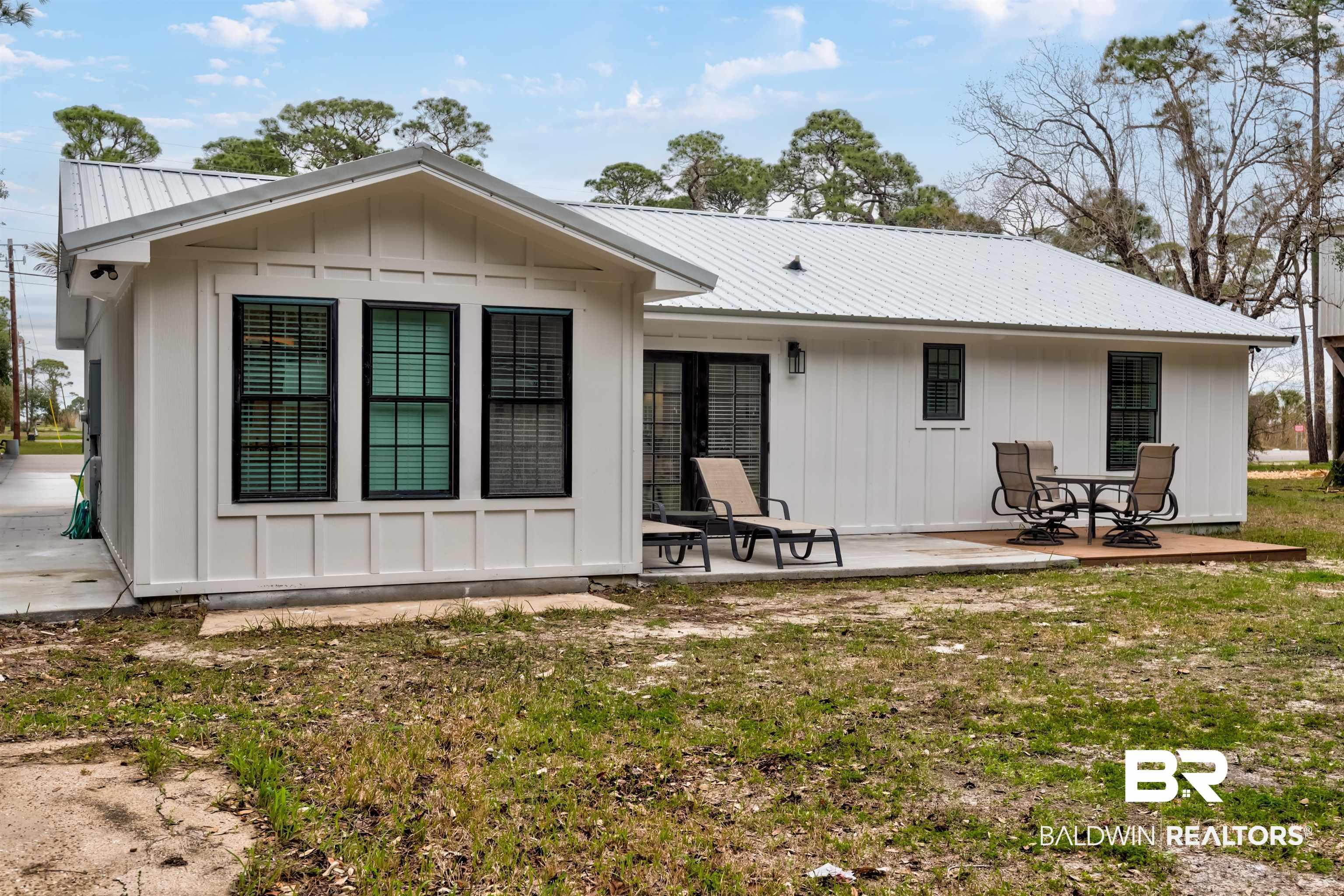 Image 2: Back of house with a metal roof, board and batten siding, and a patio