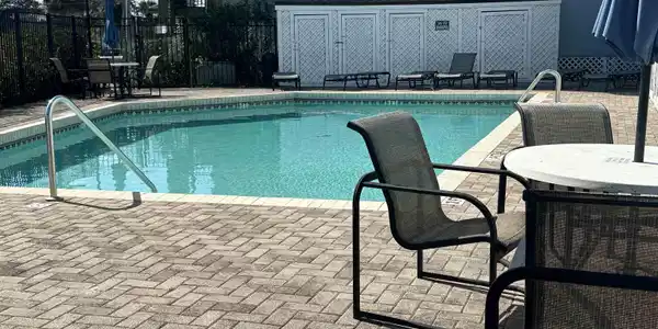 Image 2: View of swimming pool with patio surround, outdoor dining area, and an outbuilding