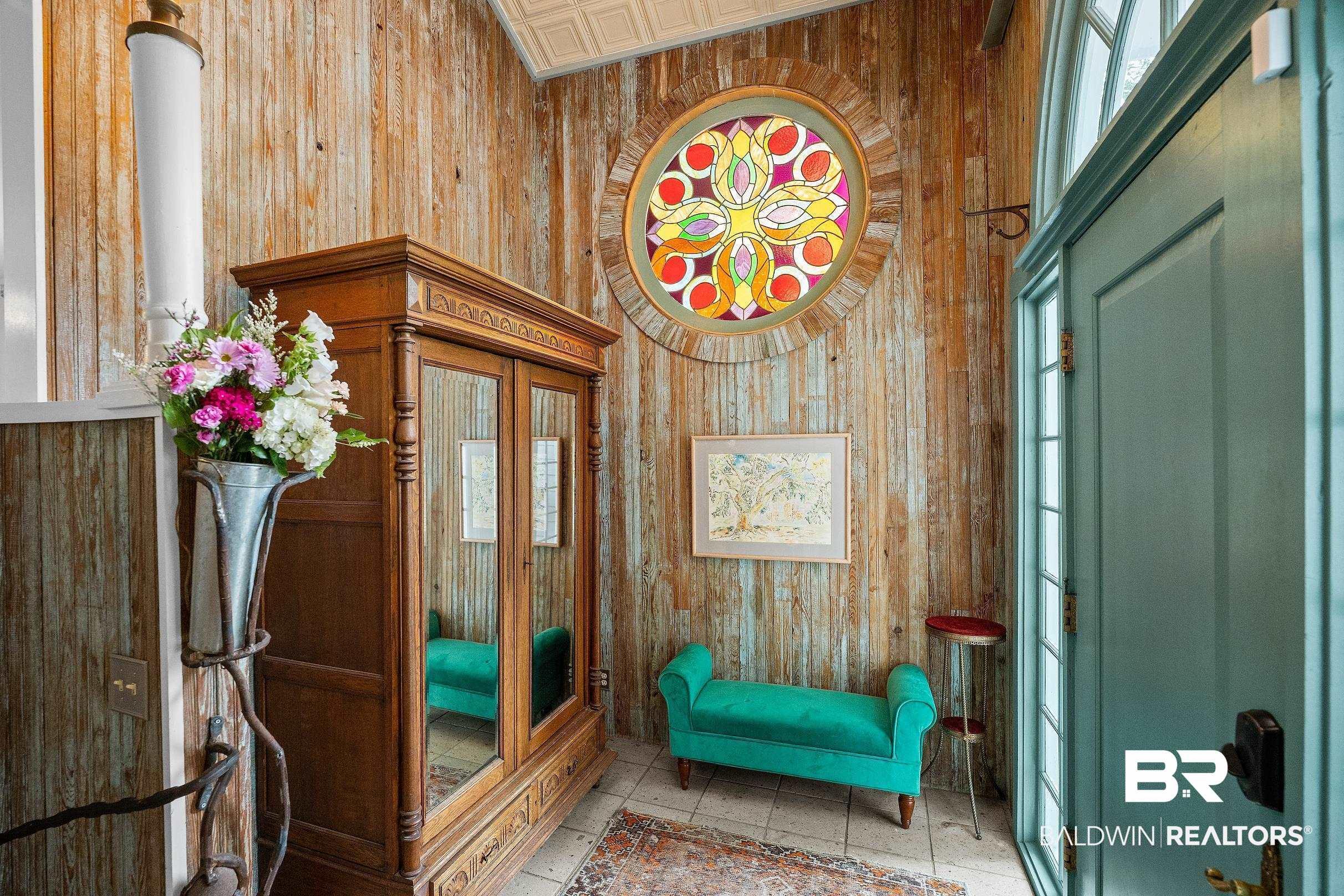 Image 3: Entryway featuring distressed wood paneling and a circular stained-glass window