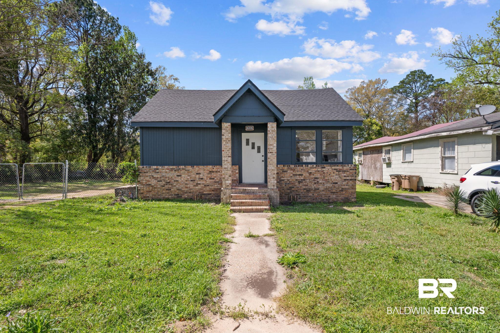 Image 2: View of front of property with a shingled roof and brick siding