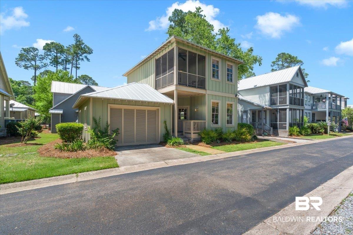 Image 3: Two-story residence featuring a screened upper balcony, a covered lower porch, and an attached garage with a concrete driveway
