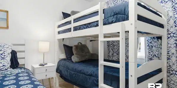 Image 4: White bunk bed with integrated ladder, white walls, light wood-finish flooring, and patterned window treatments