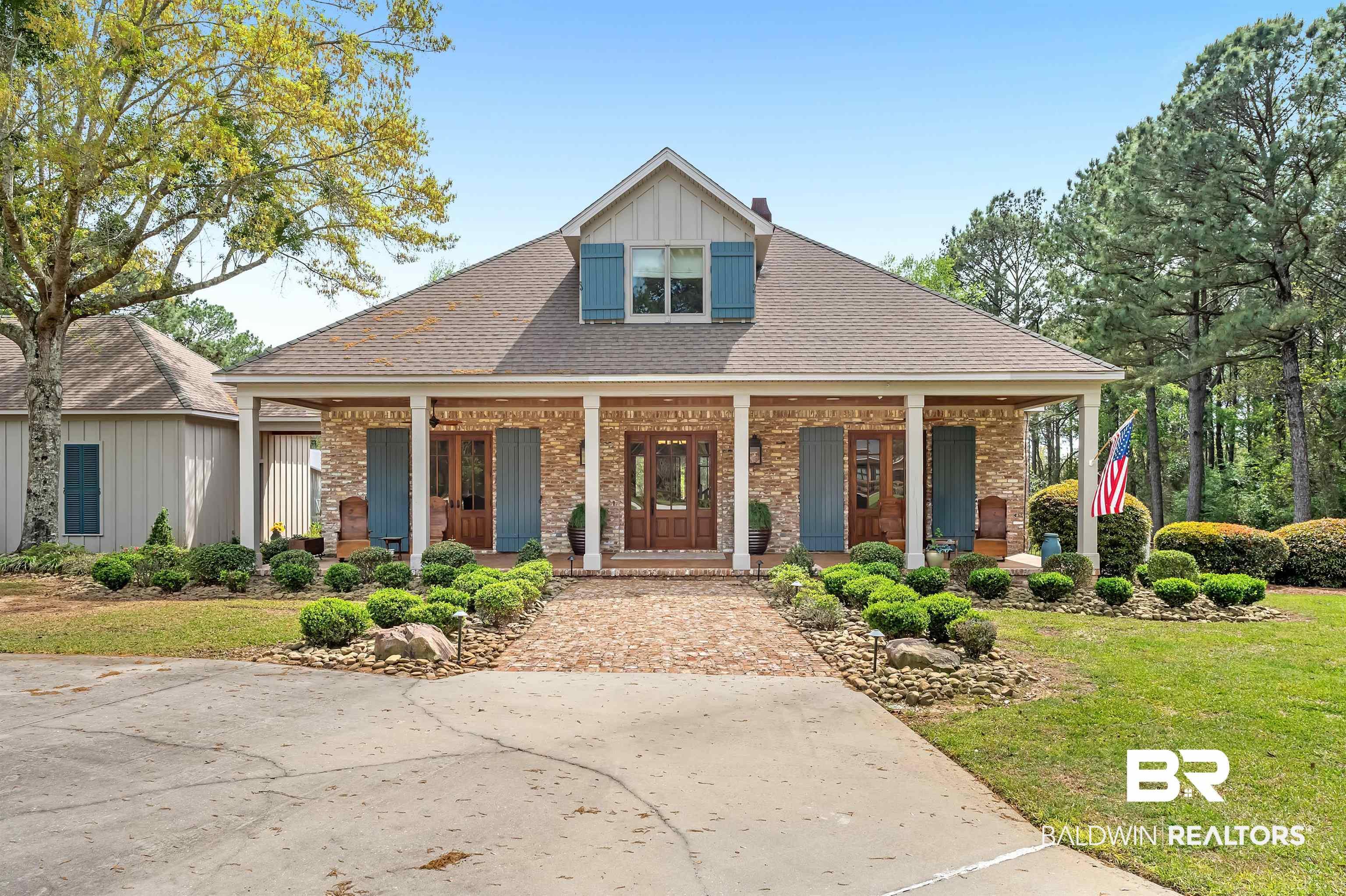 Image 1: View of front of house with roof with shingles, covered porch, a front lawn, and brick siding