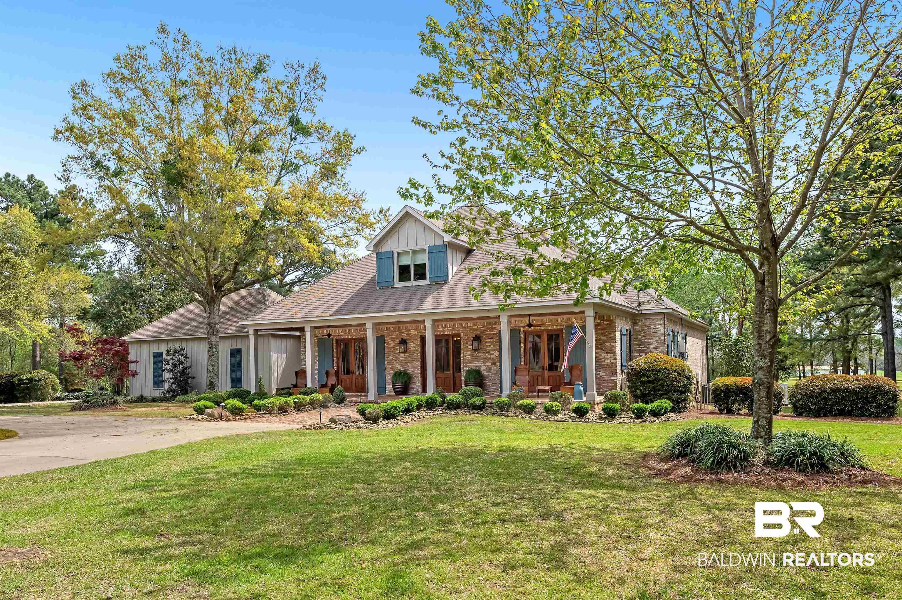 Image 2: View of front of property with covered porch, a front yard, brick siding, roof with shingles, and board and batten siding