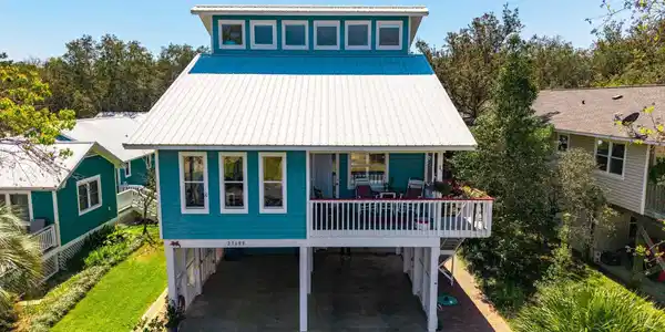 Image 2: Beach home featuring a carport, a deck, a metal roof, a patio, and driveway