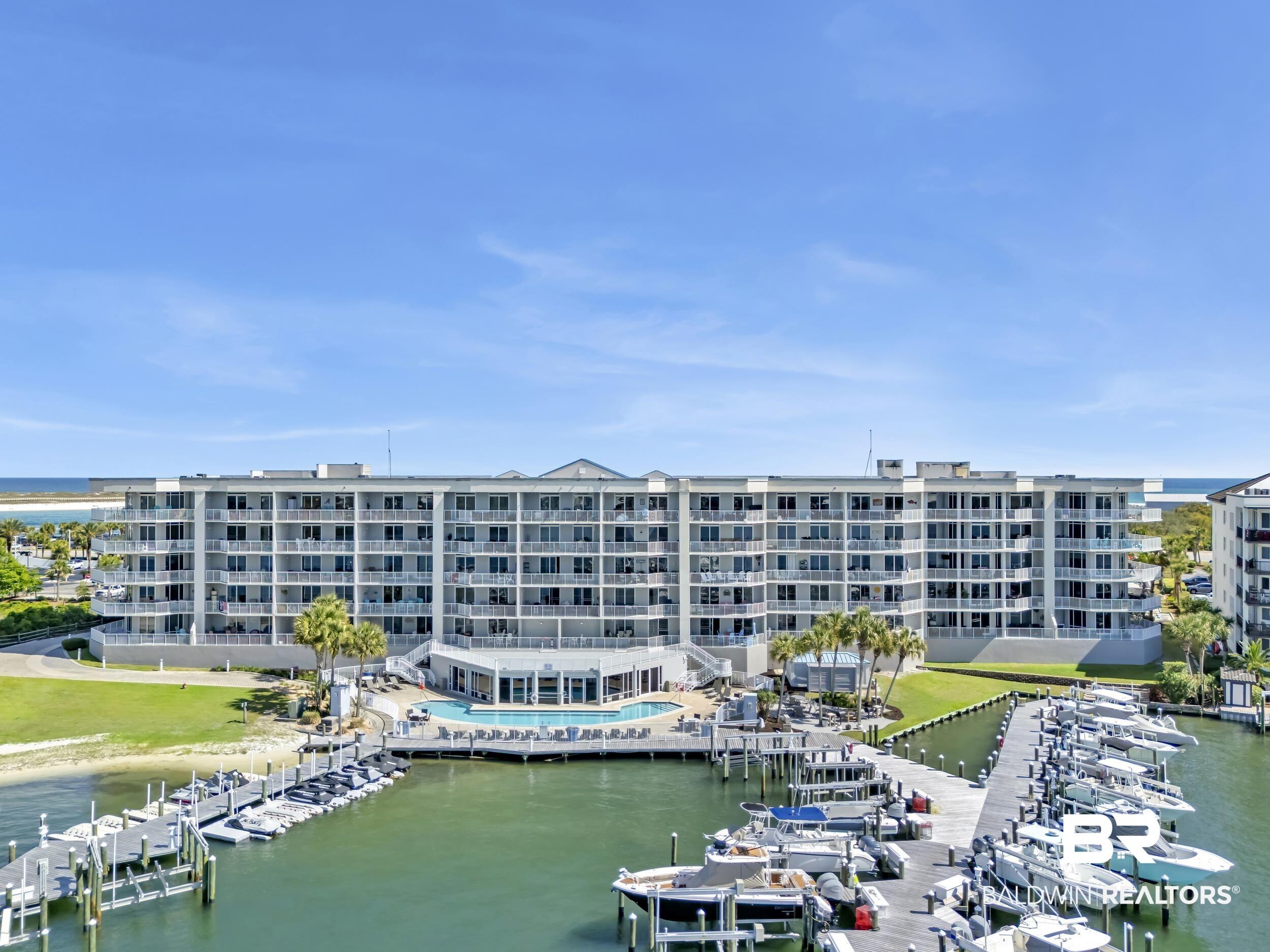 Image 1: Waterfront high-rise building featuring multiple levels of private balconies, a large outdoor swimming pool, and extensive dockage with numerous boat slips