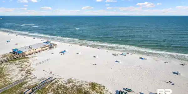 Image 2: Expansive beachfront with white sand and clear blue water