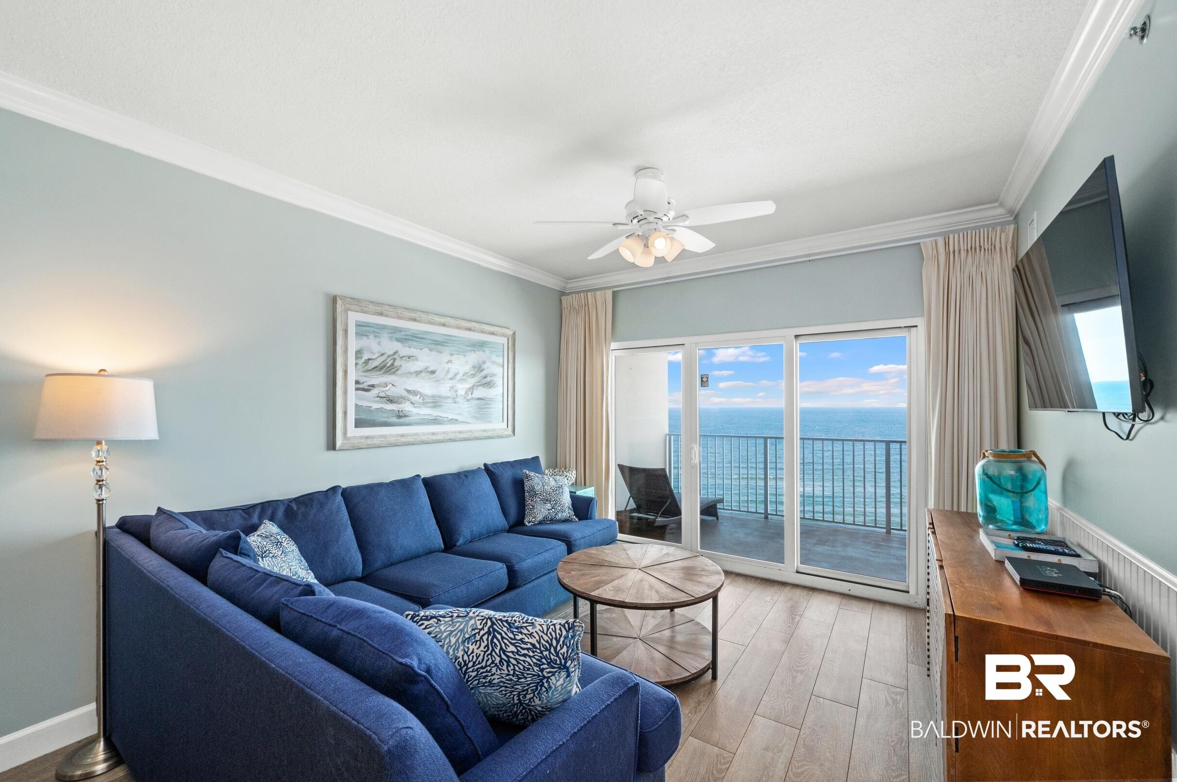 Image 3: Sliding glass doors opening to a balcony with water views, wood-finish flooring, crown molding, and a ceiling fan