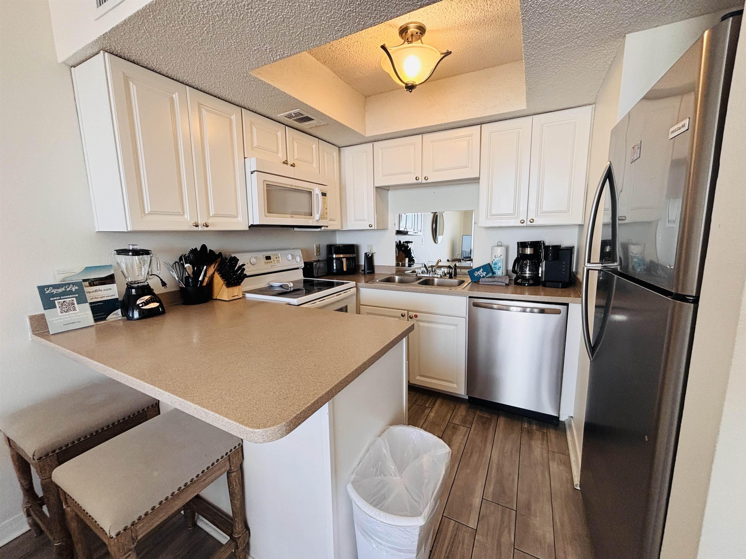 Image 2: Kitchen featuring stainless steel appliances, white cabinets, a peninsula, dark wood-type flooring, and a tray ceiling