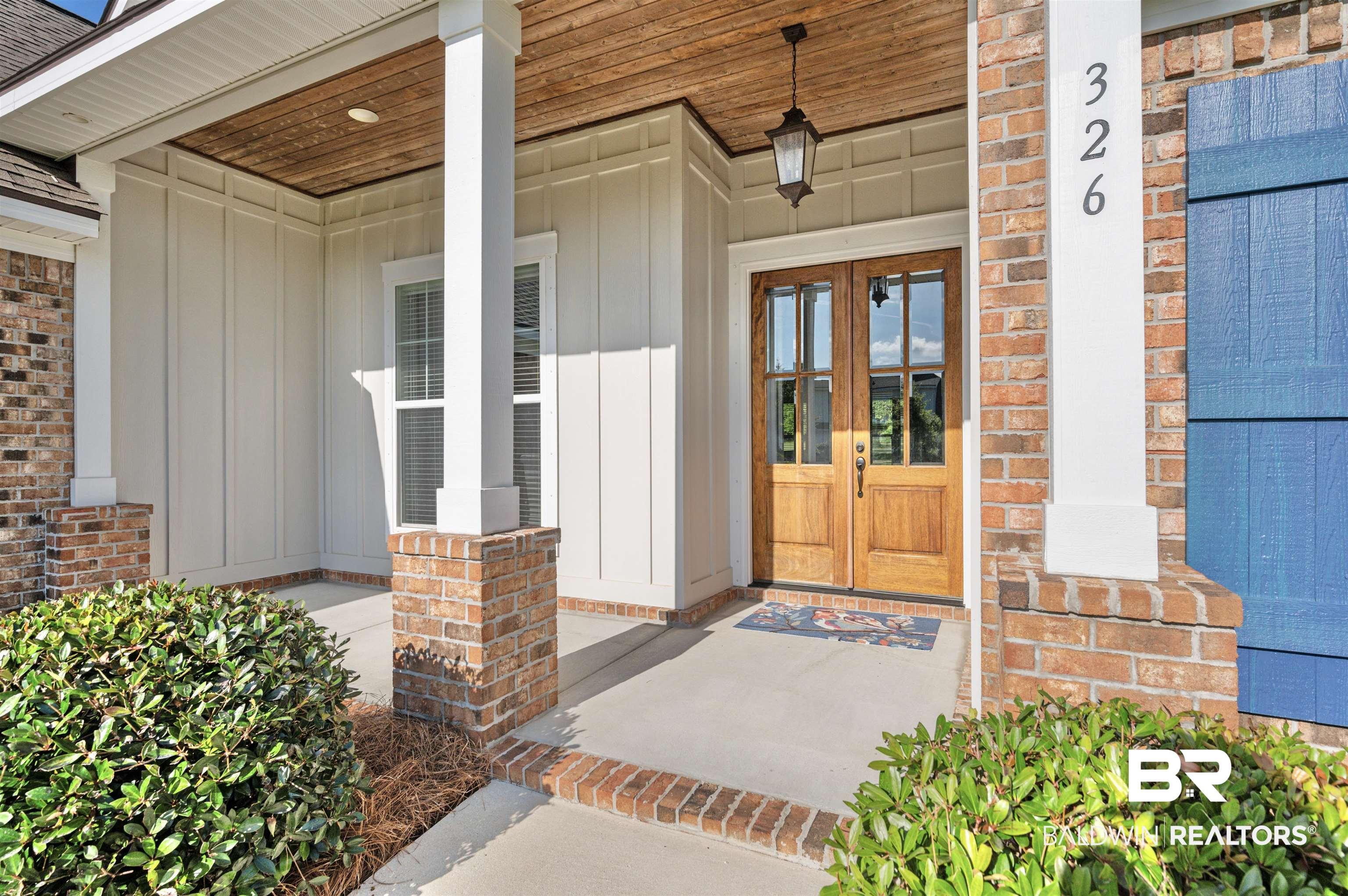 Image 2: Covered entryway featuring a wood-finish ceiling, double-door entry with divided lites, board and batten siding, brick accents, and a hanging lantern light fixture