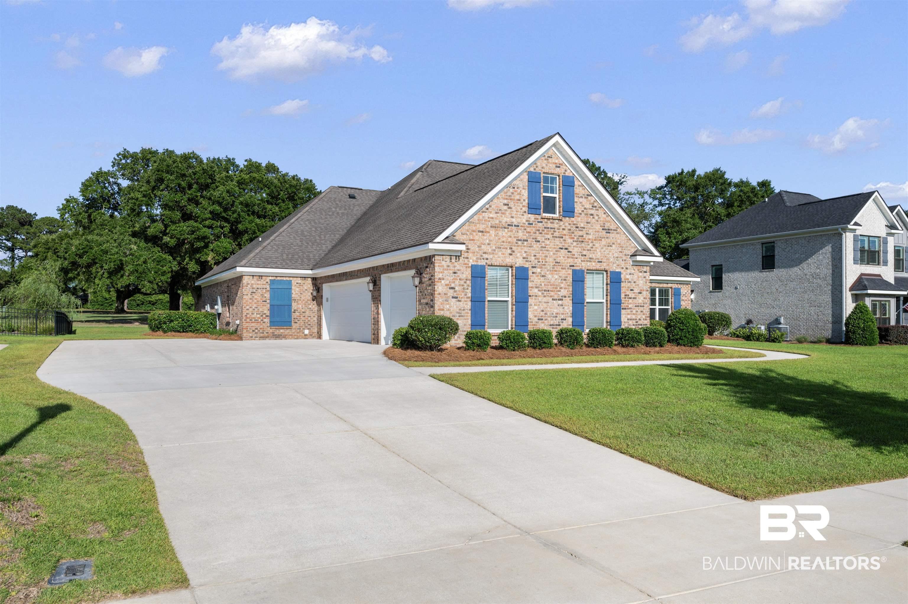 Image 3: Brick exterior with blue window shutters, featuring a two-car garage, concrete driveway, and manicured front lawn