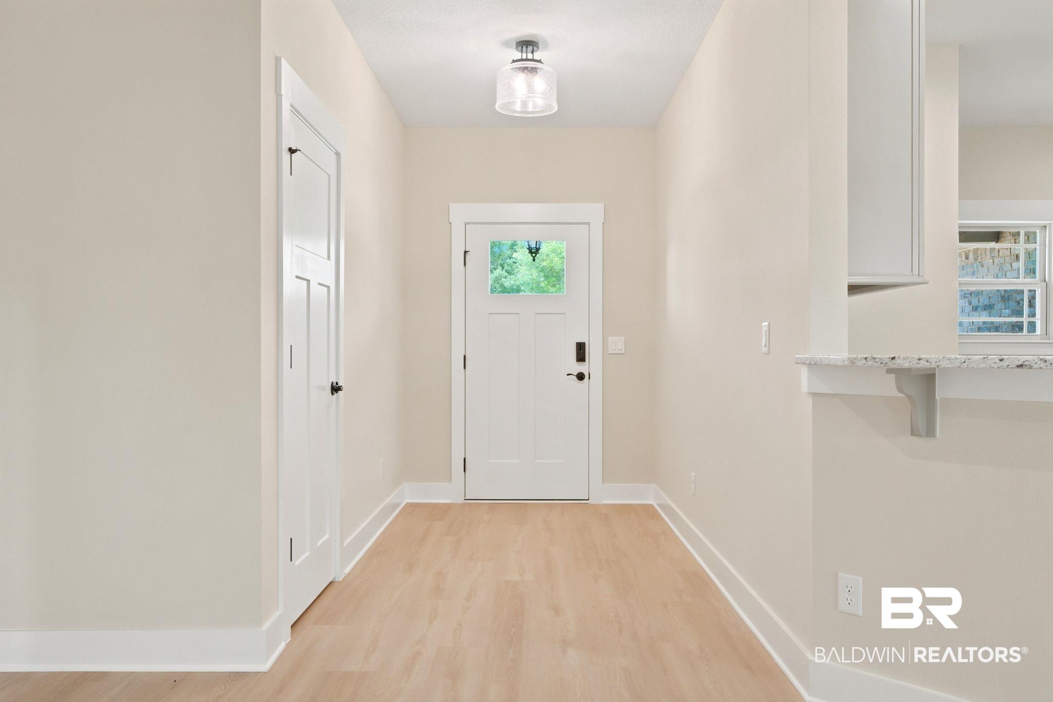Image 2: Foyer featuring light wood-finish flooring, a contemporary flush mount light fixture, and a paneled entry door with a frosted glass insert