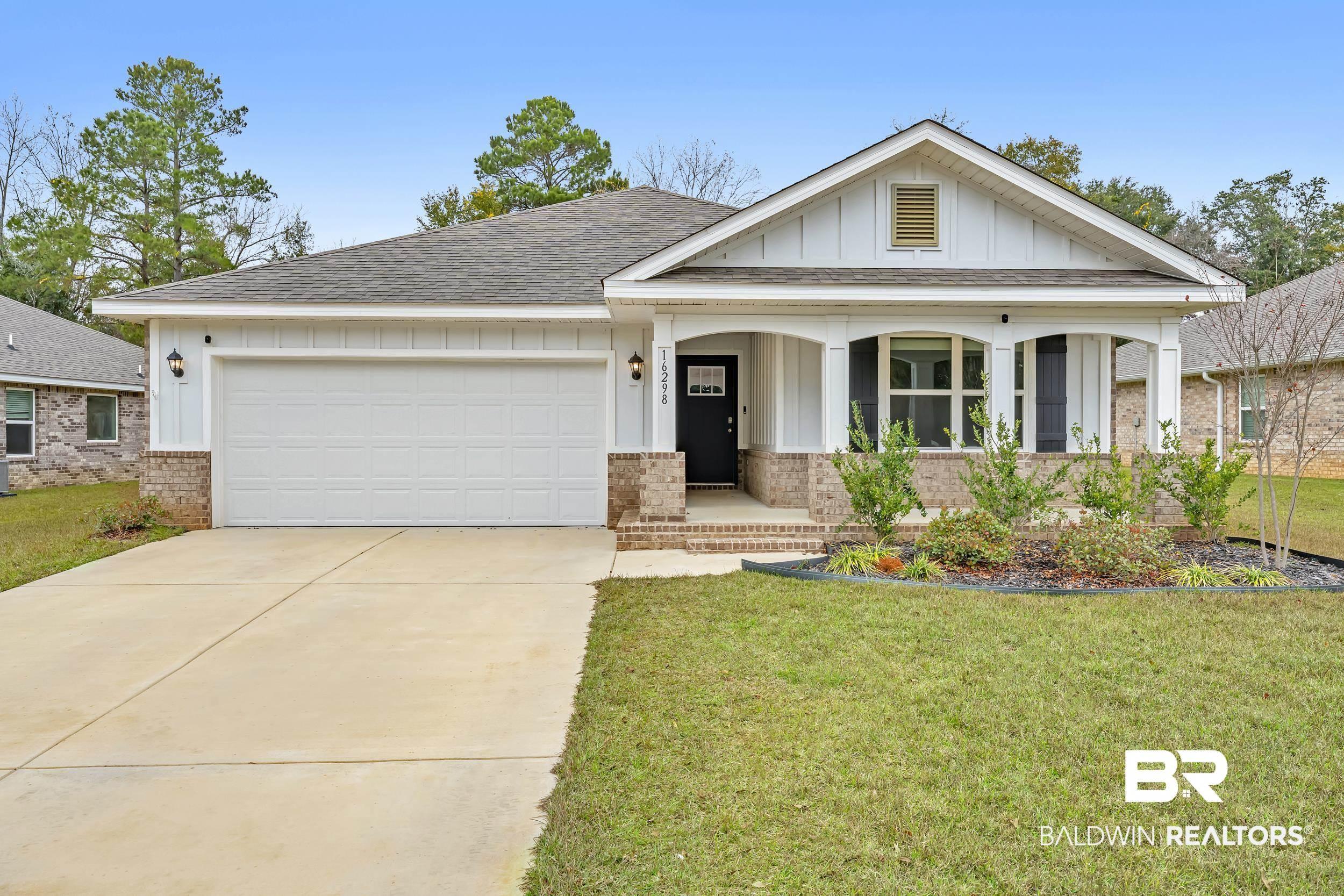 Image 2: View of front of house with board and batten siding, brick siding, roof with shingles, covered porch, and a front yard