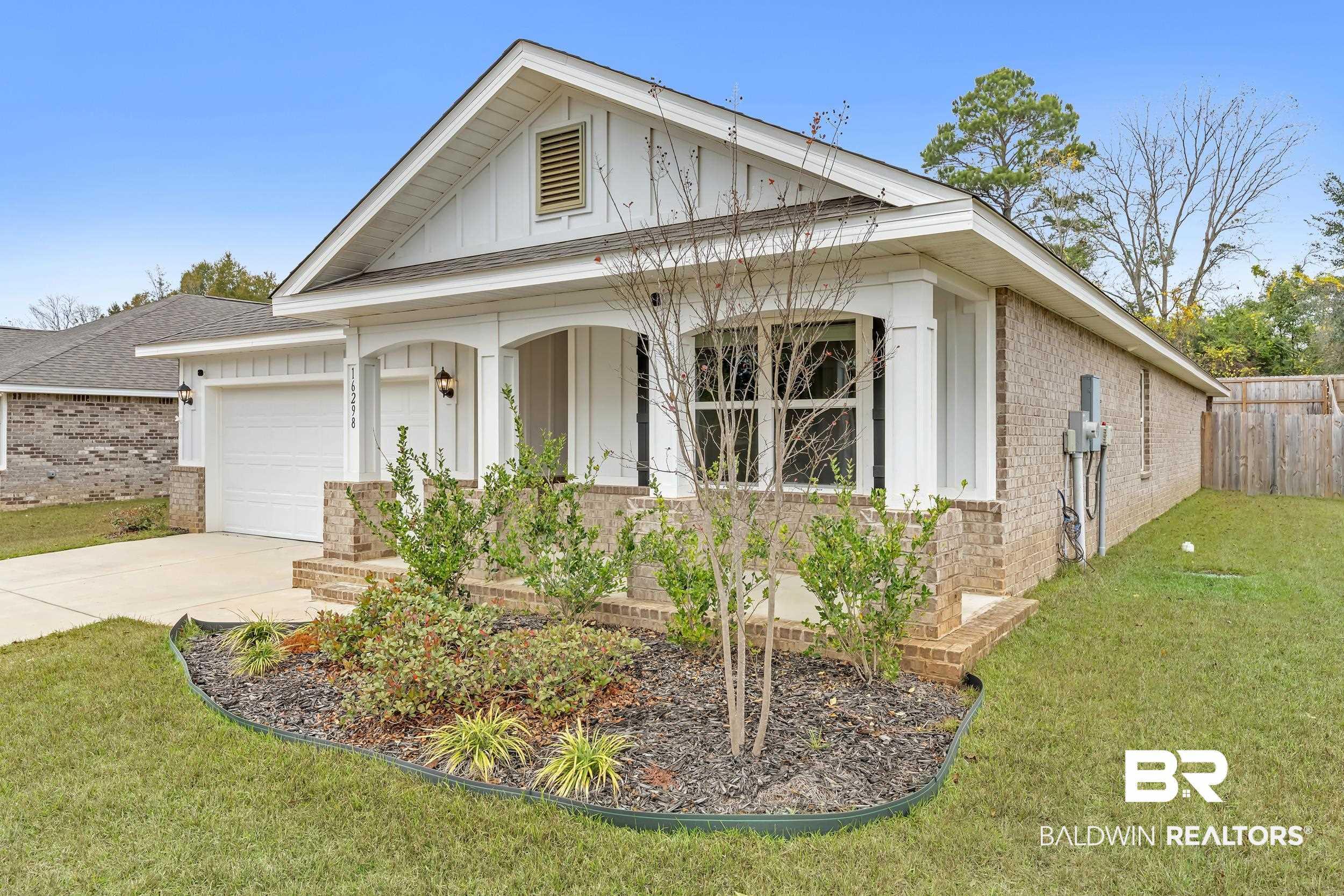Image 4: View of front of house with brick siding, covered porch, driveway, board and batten siding, and a garage