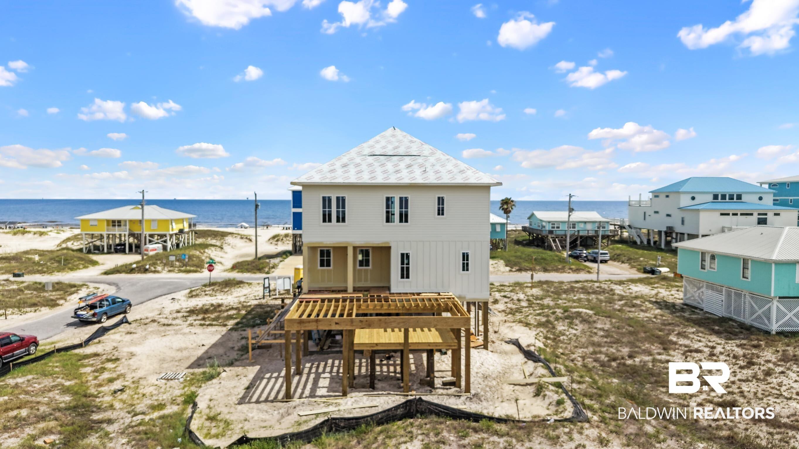 Image 3: New construction home featuring a light-colored exterior, multiple windows, and a prominent deck structure