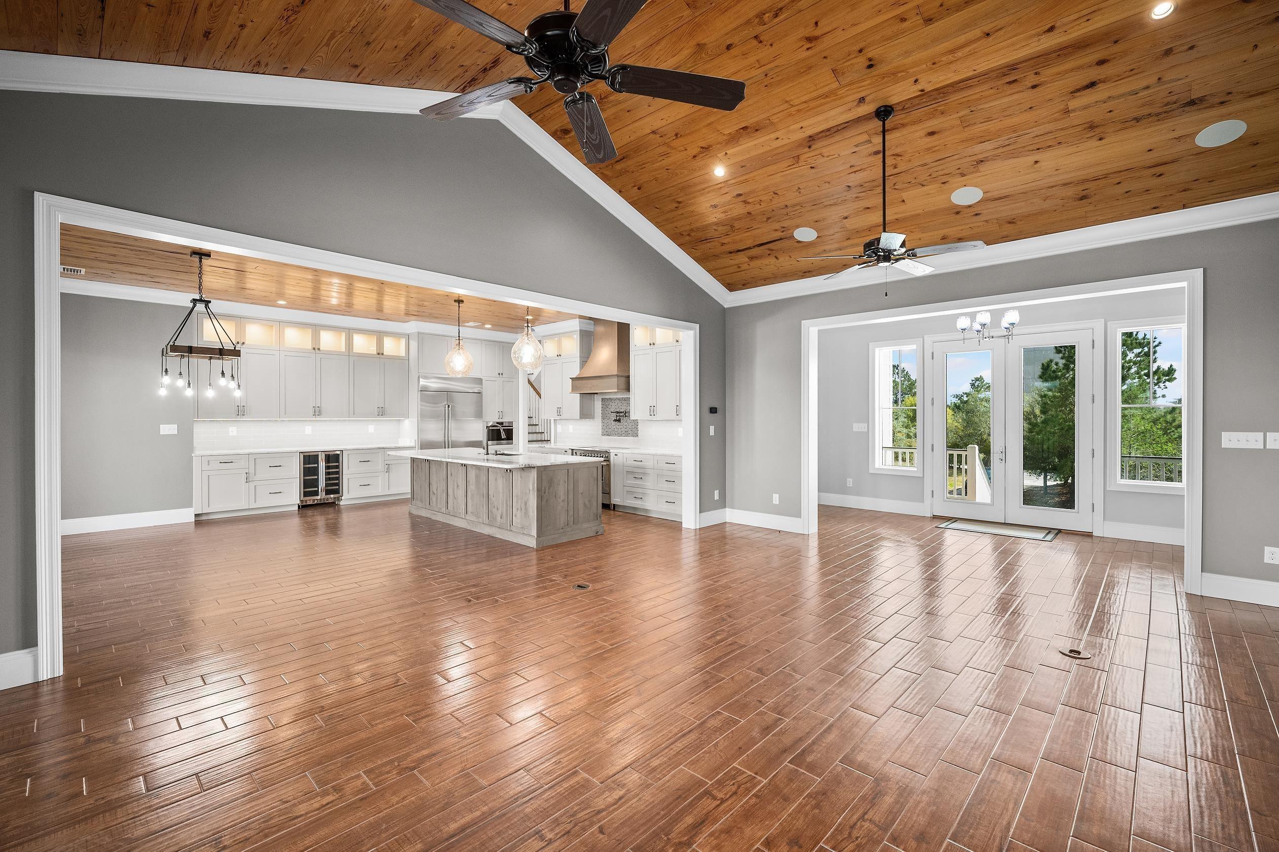 Image 3: Unfurnished living room with a high wooden ceiling, ornamental molding, wood tiled floors, beverage cooler, and recessed lighting