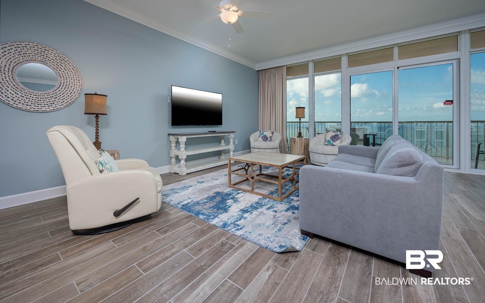 Image 3: Living area featuring wood finish floors, crown molding, expansive windows, and ceiling fan