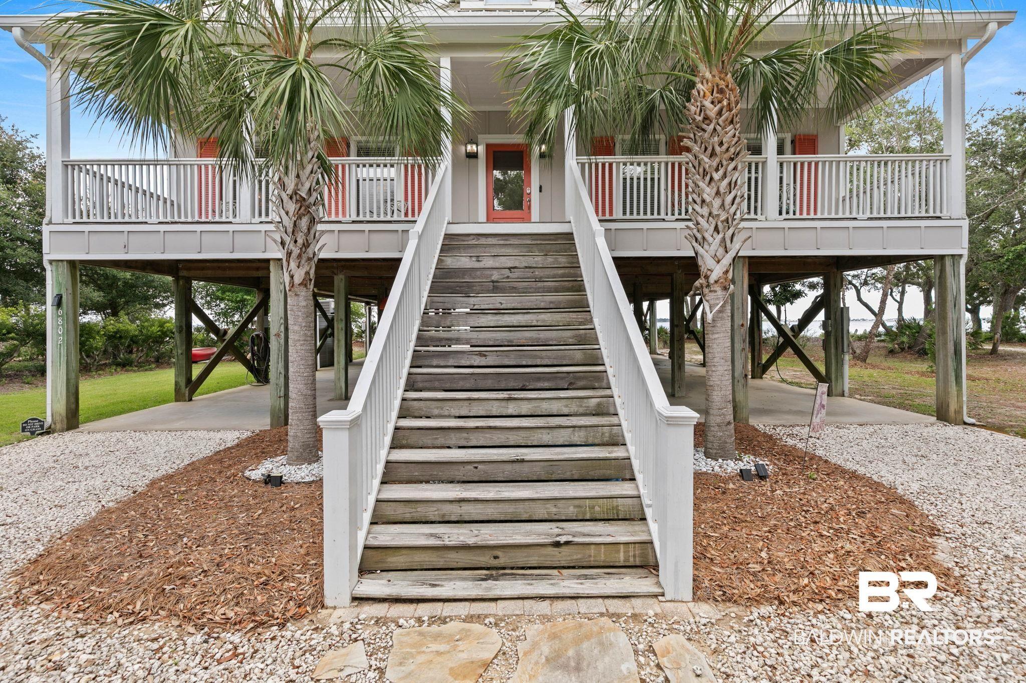Image 3: Elevated coastal residence featuring a prominent wooden staircase and a deep front porch