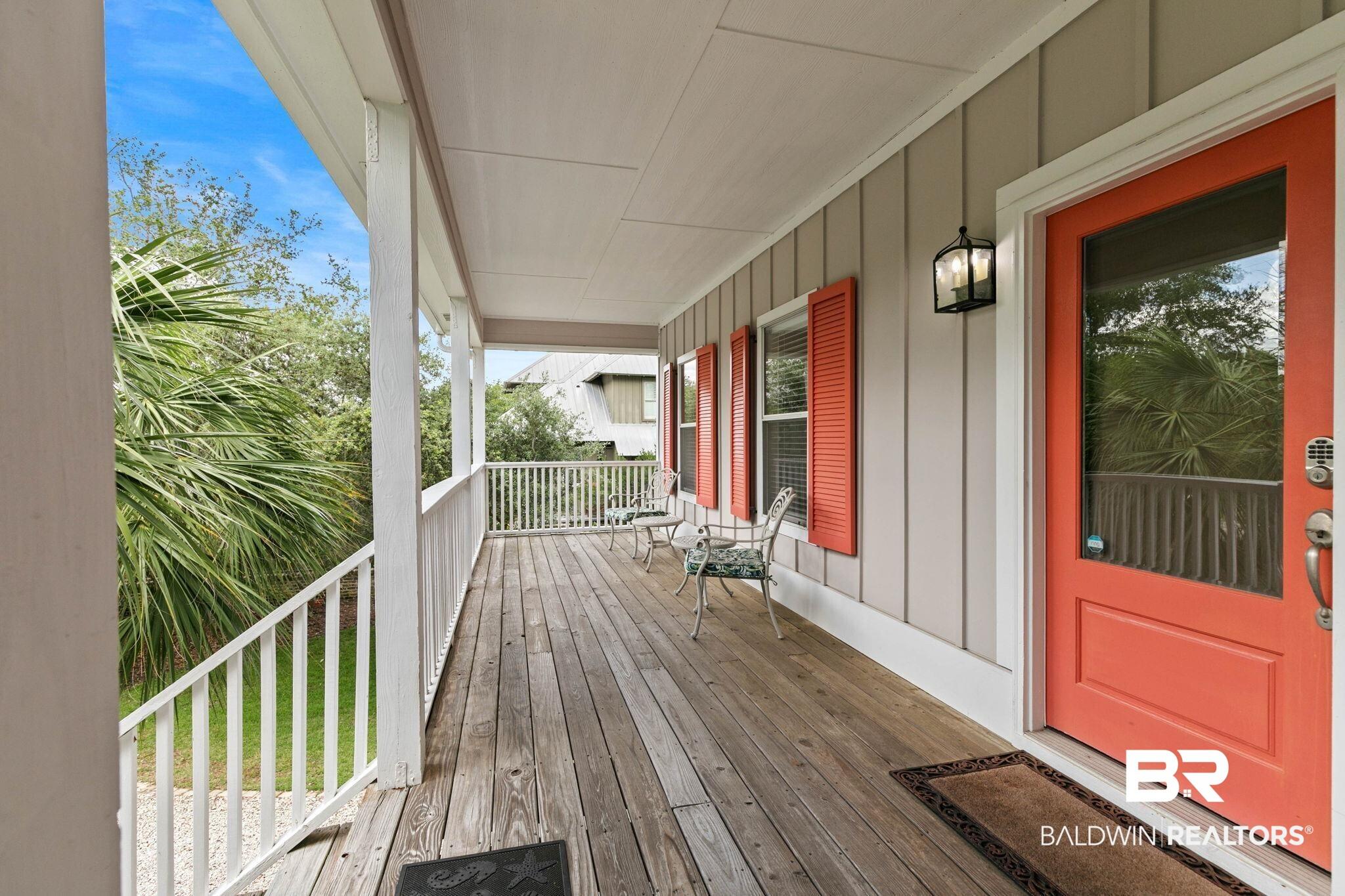 Image 4: Spacious covered porch with a wood-finish floor, white railing, and paneled siding