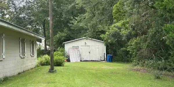 Image 2: Expansive green lawn with mature trees and a detached shed featuring double doors