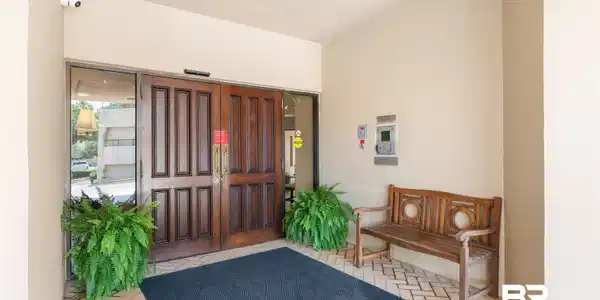 Image 3: Secure entry featuring double panel wood doors with glass sidelights, an intercom system, and a surveillance camera