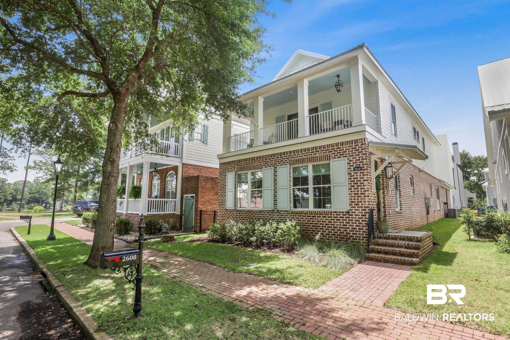 Image 1: View of front facade featuring brick siding, a balcony, and a front yard