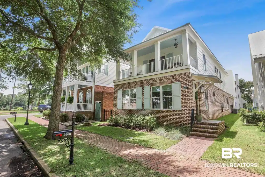 Image 1: View of front facade featuring brick siding, a balcony, and a front yard