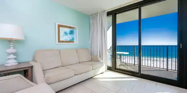 Image 3: Tiled living area featuring view of water and beach, expansive windows, and a ceiling fan