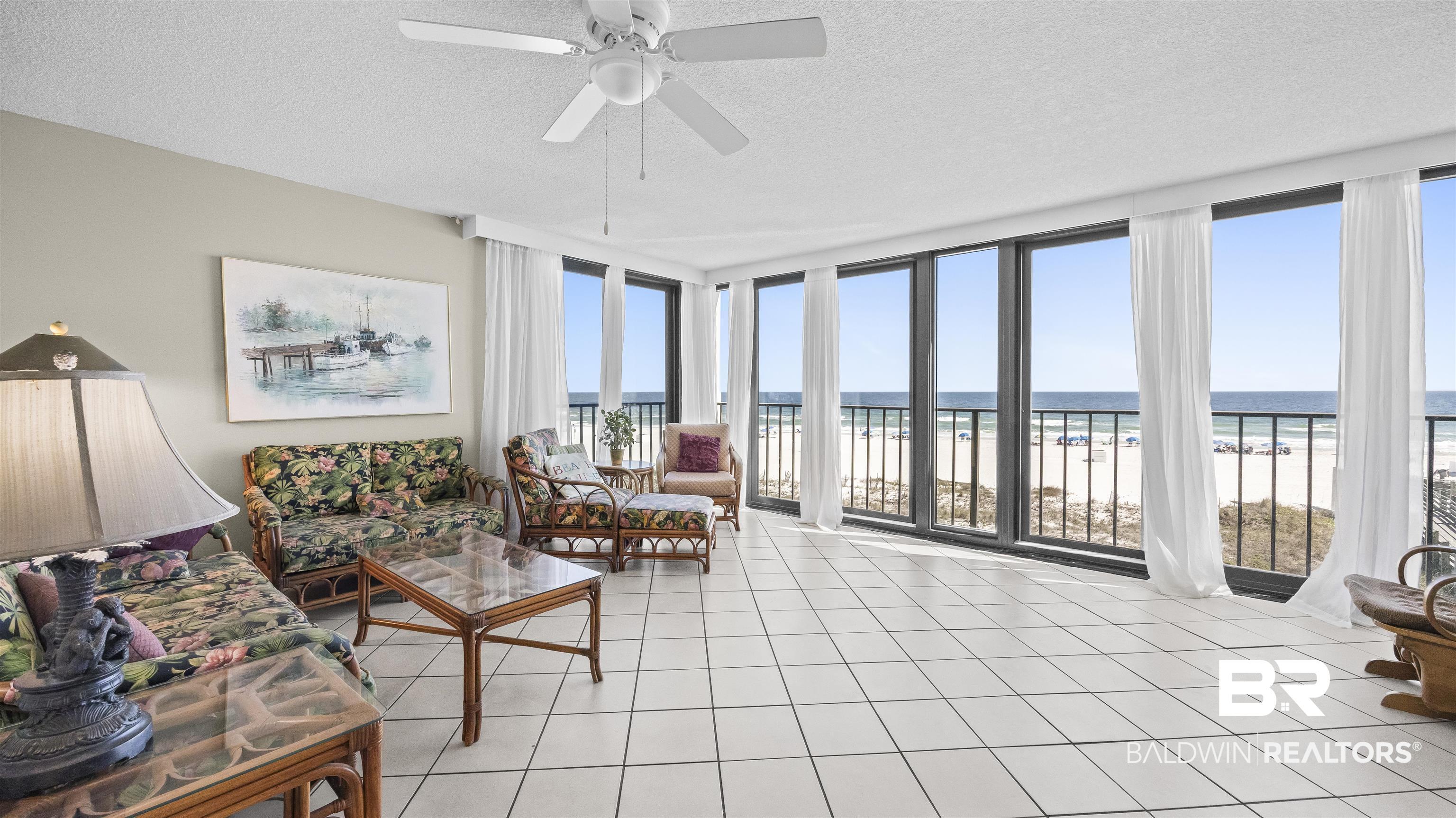 Image 1: Sun Room with floor to ceiling windows, a textured ceiling, view of water and beach, and ceiling fan