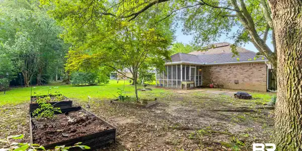 Image 3: Expansive backyard featuring a screened porch, brick exterior, and mature trees