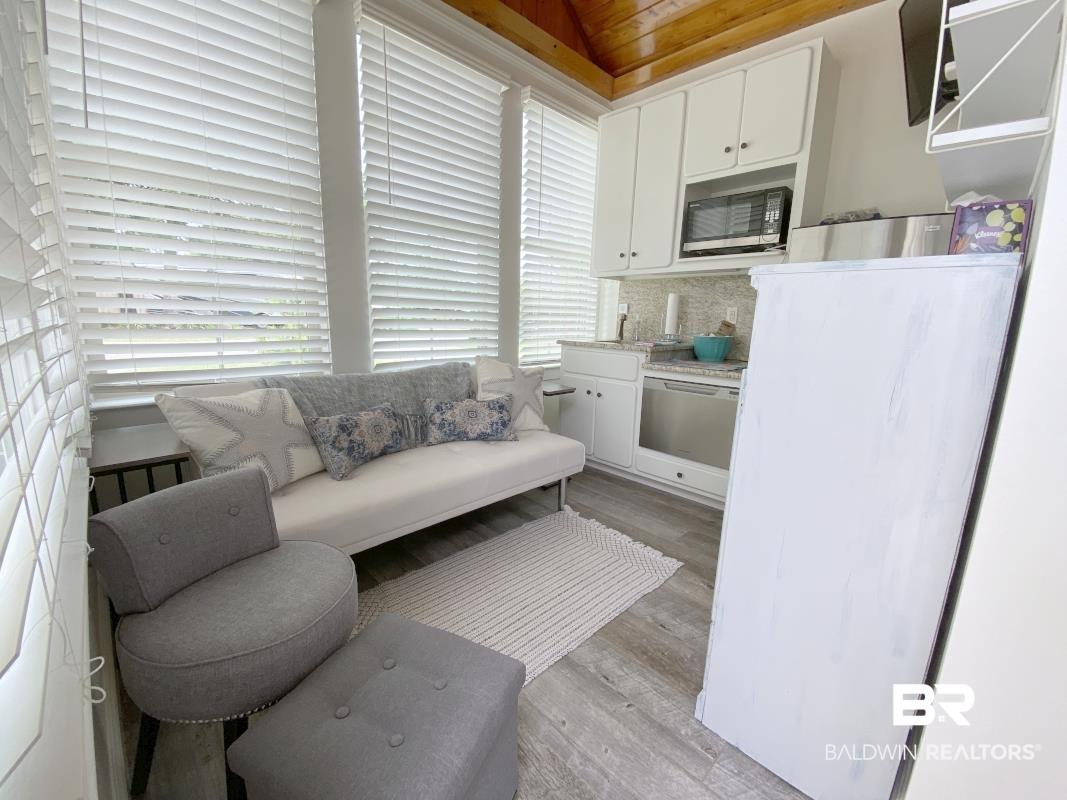 Image 4: Sunroom featuring a wood-finish vaulted ceiling, white window blinds, wood-finish flooring, white cabinetry, and stainless steel appliances
