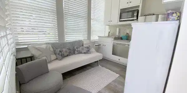 Image 4: Sunroom featuring a wood-finish vaulted ceiling, white window blinds, wood-finish flooring, white cabinetry, and stainless steel appliances