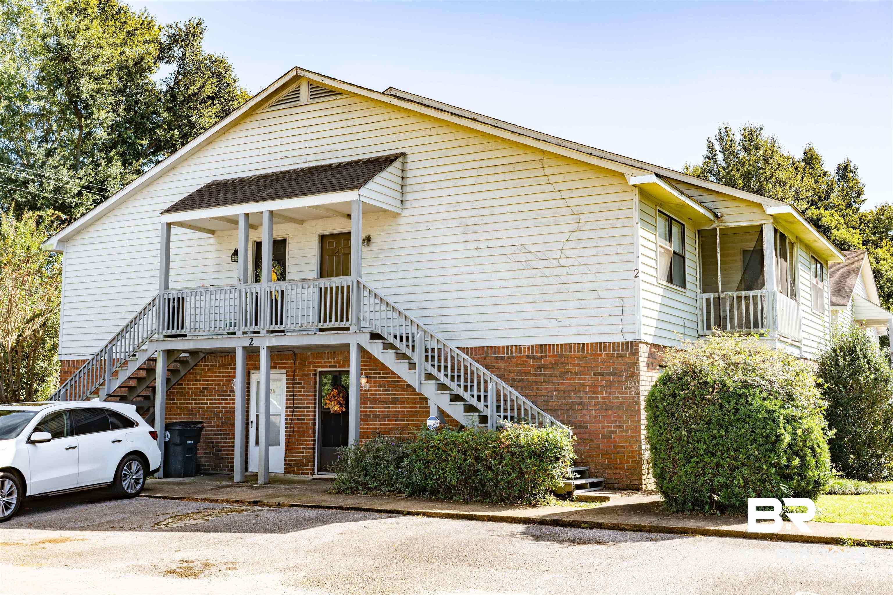 Image 1: View of front of home with stairs, brick siding, and roof with shingles