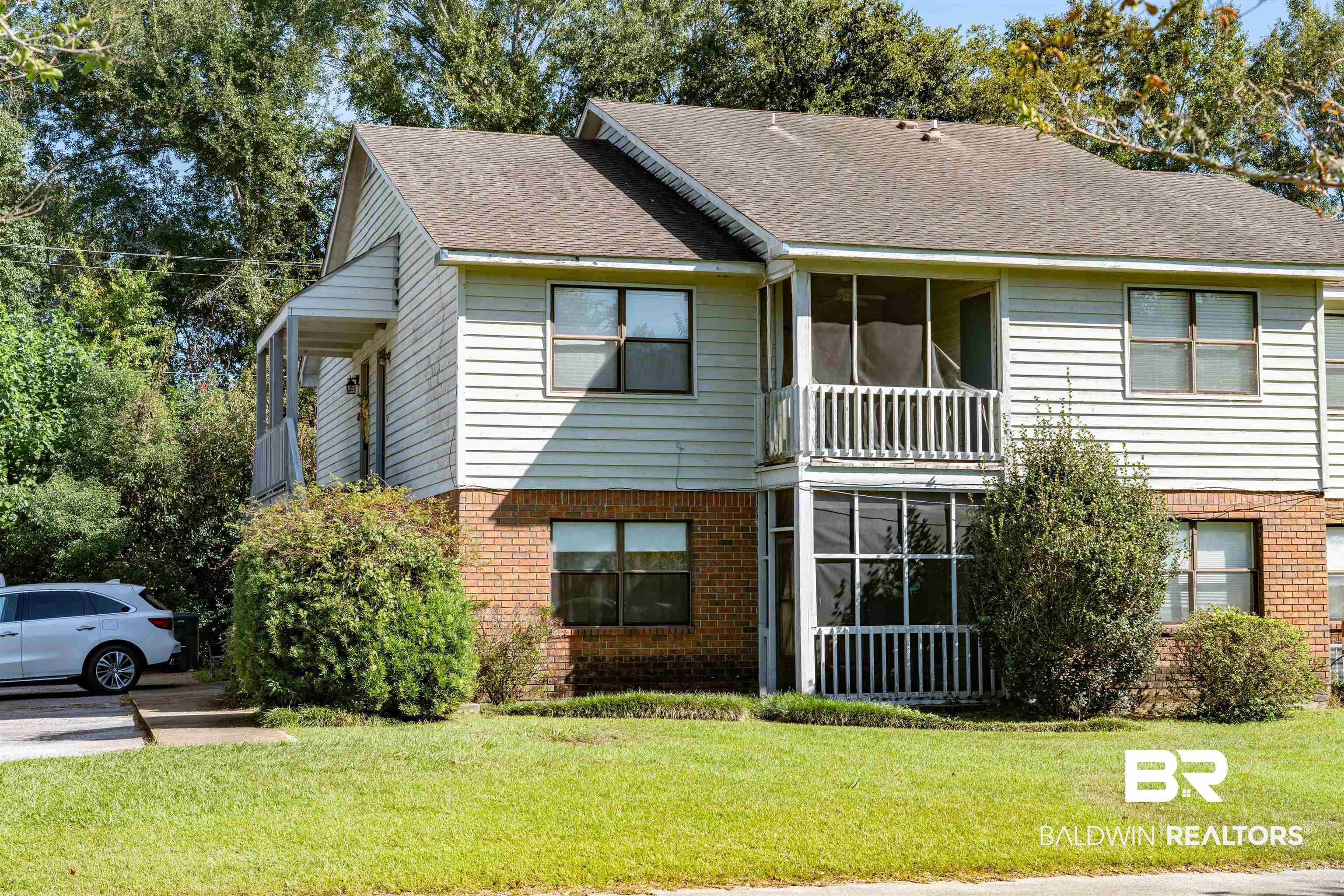 Image 3: View of front of home with brick siding, roof with shingles, and a front lawn