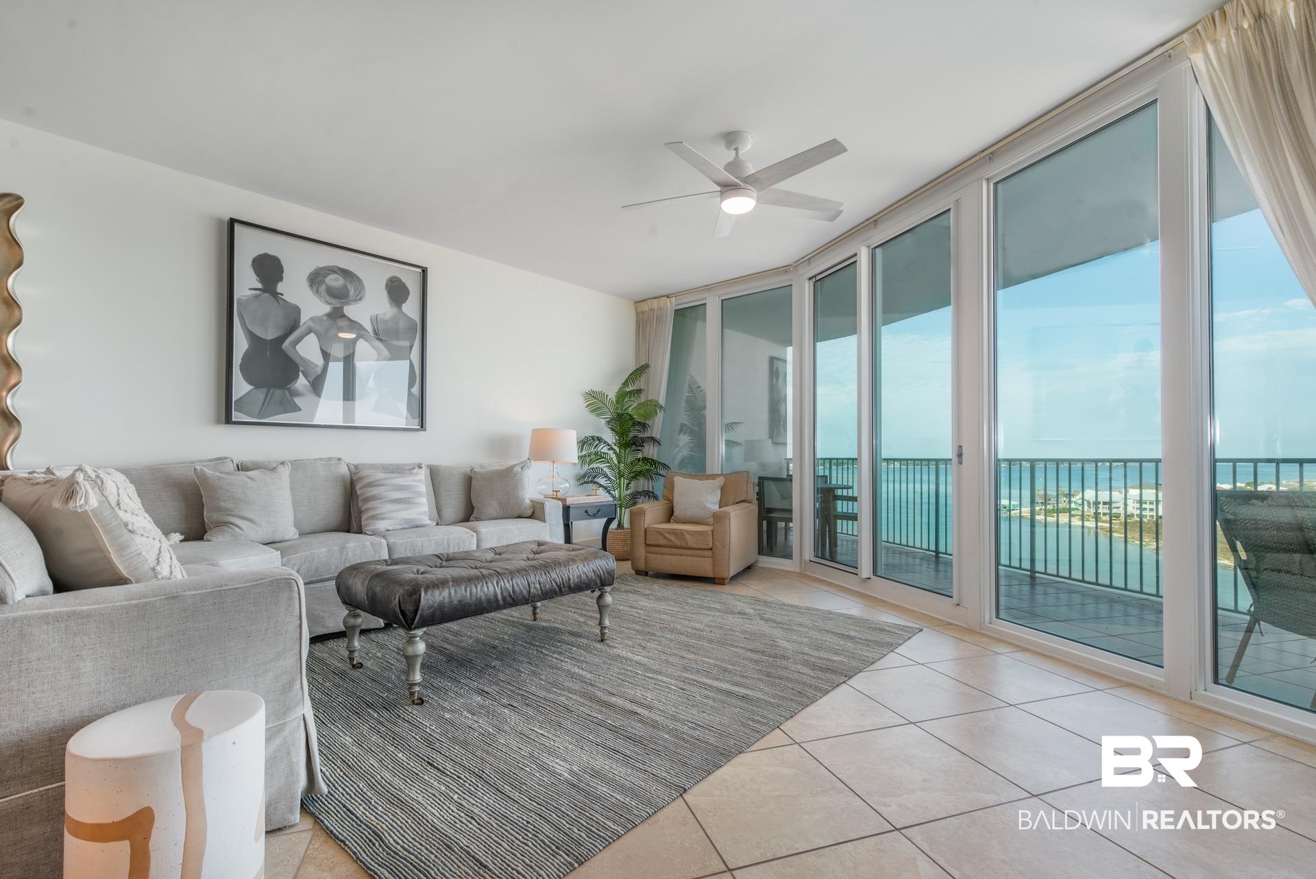 Image 2: Living room with floor to ceiling windows, ceiling fan, and light tile patterned floors