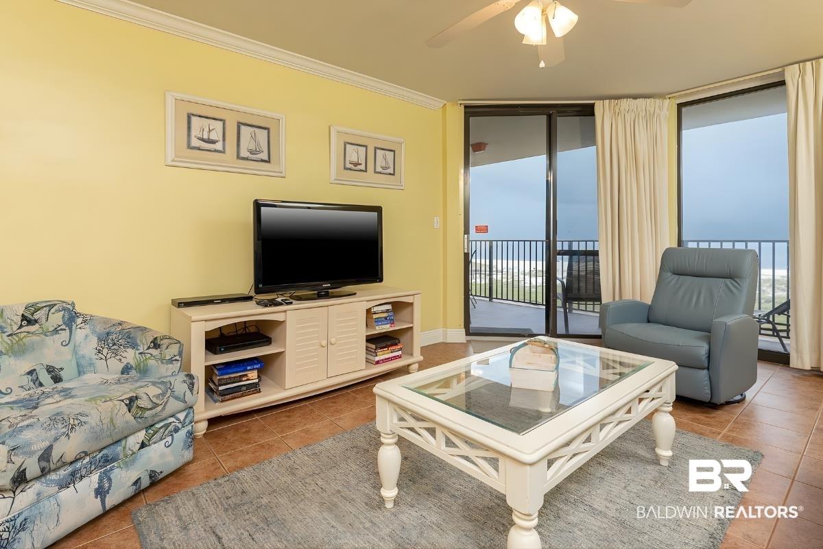 Image 4: Tiled living room featuring floor to ceiling windows, ornamental molding, and ceiling fan