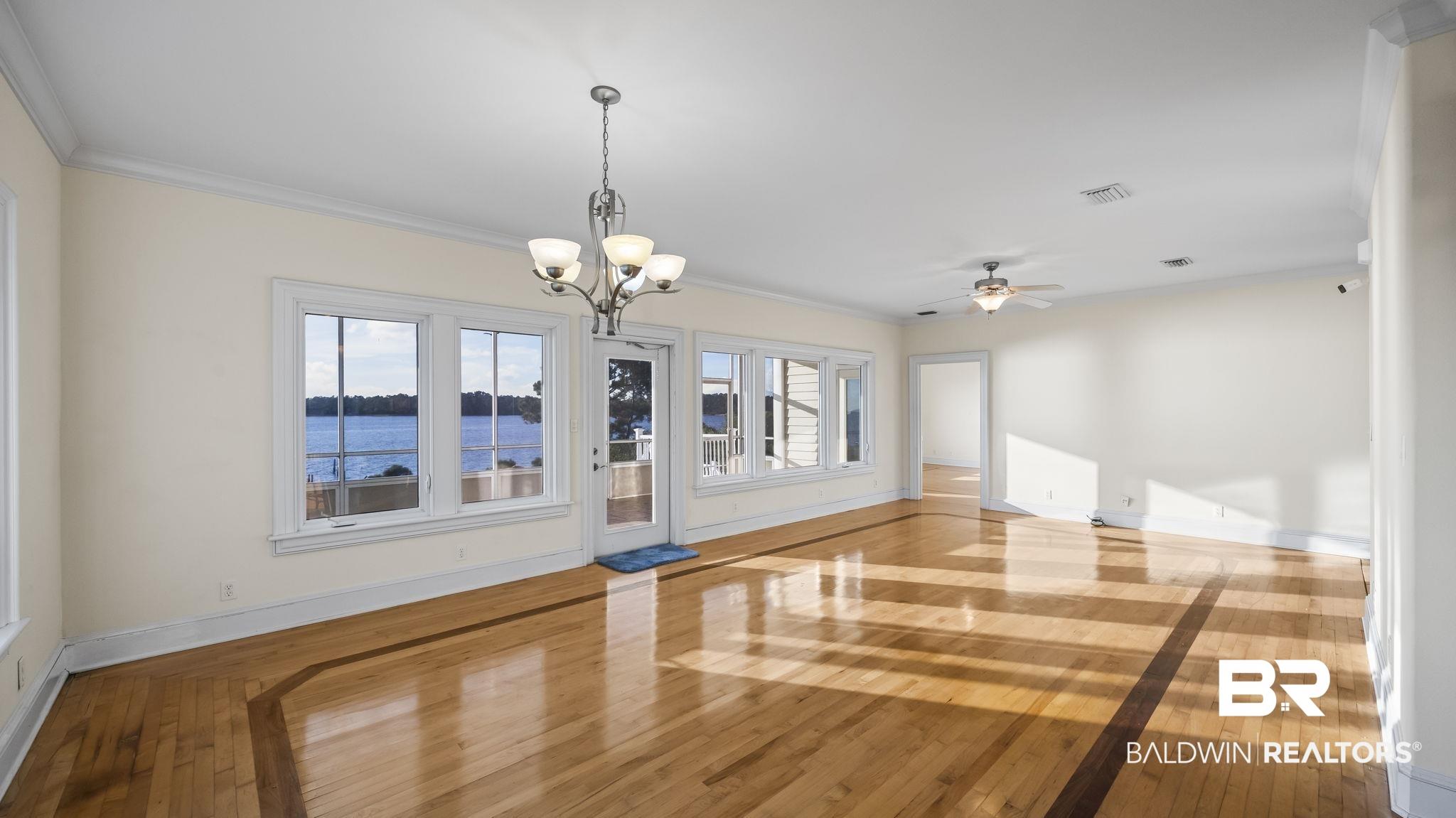 Image 4: Unfurnished dining area featuring light wood-type flooring, crown molding, a ceiling fan, a chandelier, and a water view
