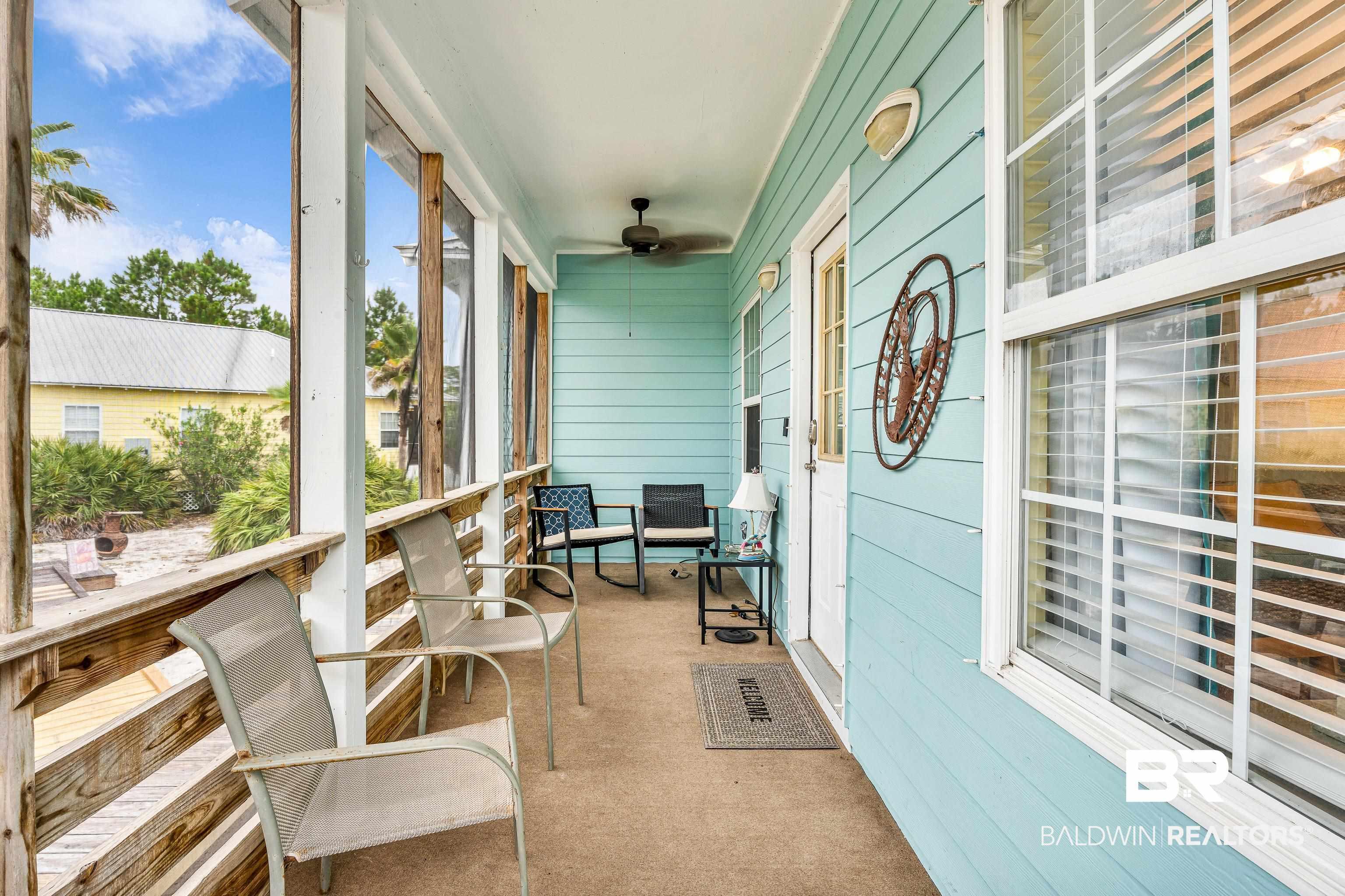 Image 2: Screened porch featuring light blue siding, a white entry door, multiple windows with horizontal blinds, a ceiling fan, and sconce lighting