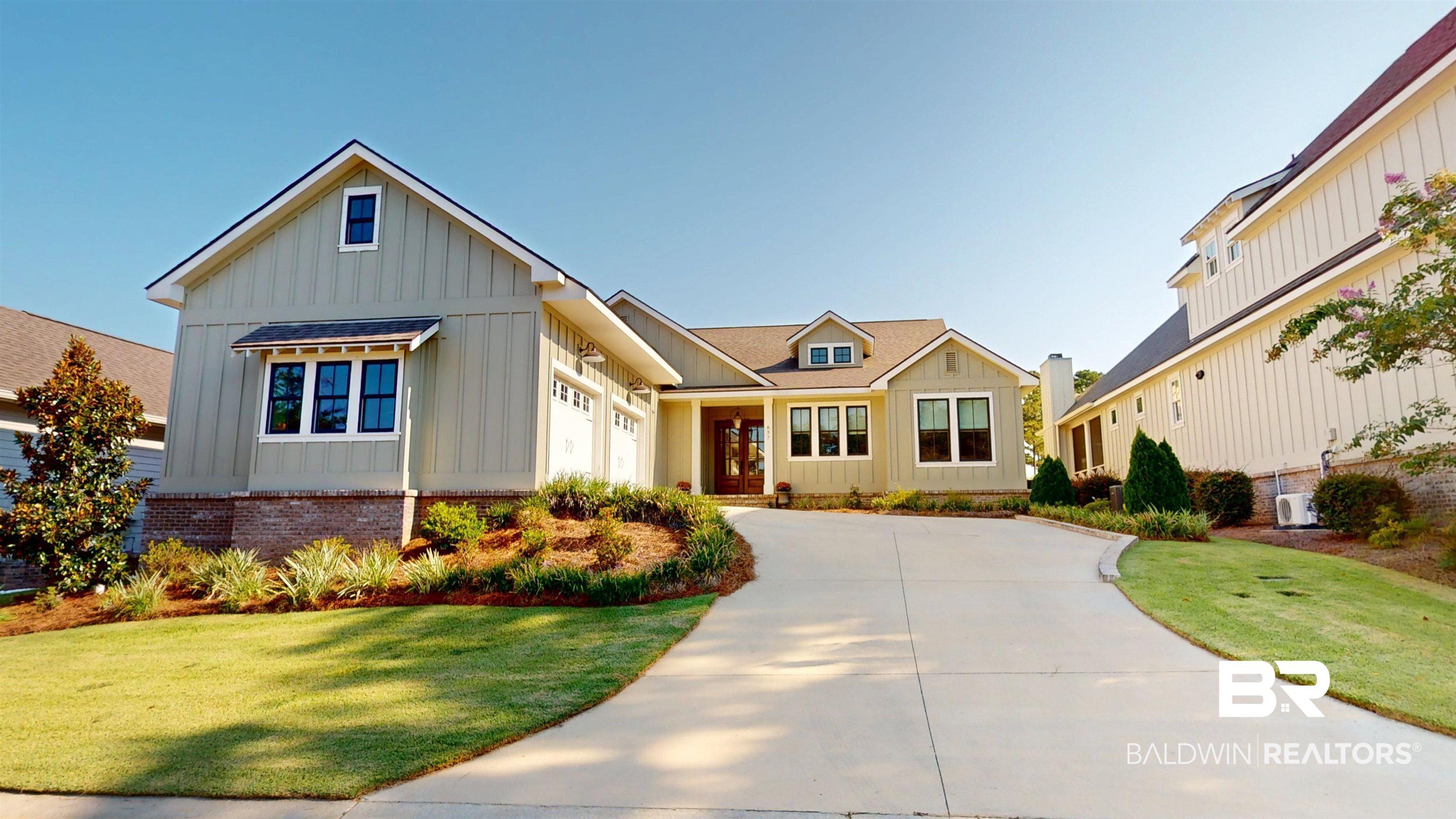 Image 3: View of front of home featuring board and batten siding, driveway, a front lawn, and a garage