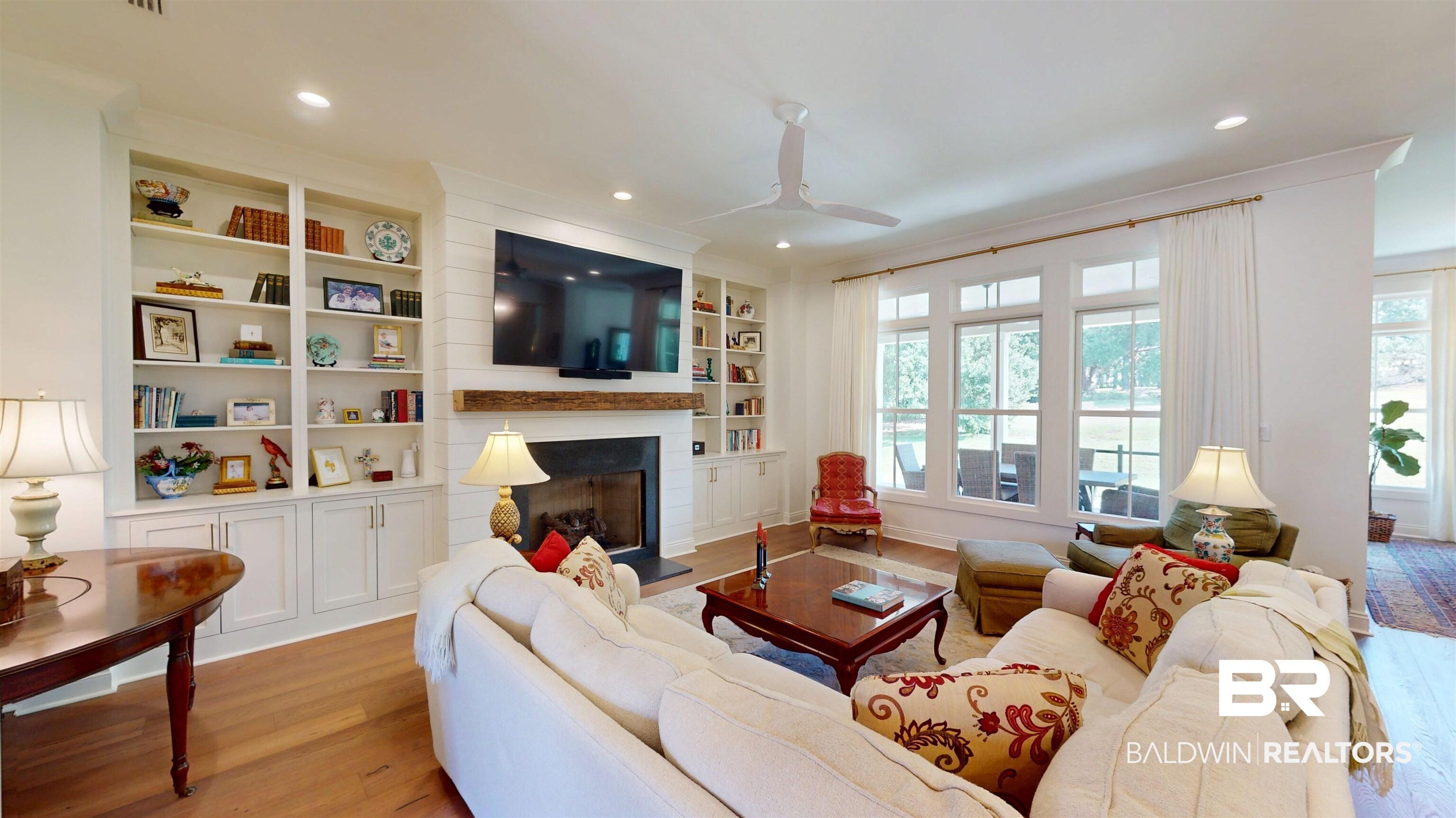 Image 4: Living room featuring light wood-type flooring, a fireplace with raised hearth, a ceiling fan, recessed lighting, and built in features