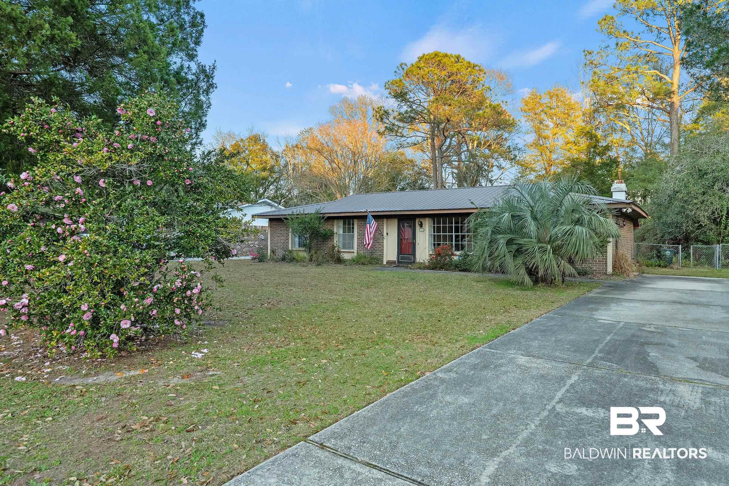 Image 3: View of front of property with concrete driveway, brick siding, a metal roof, and a chimney