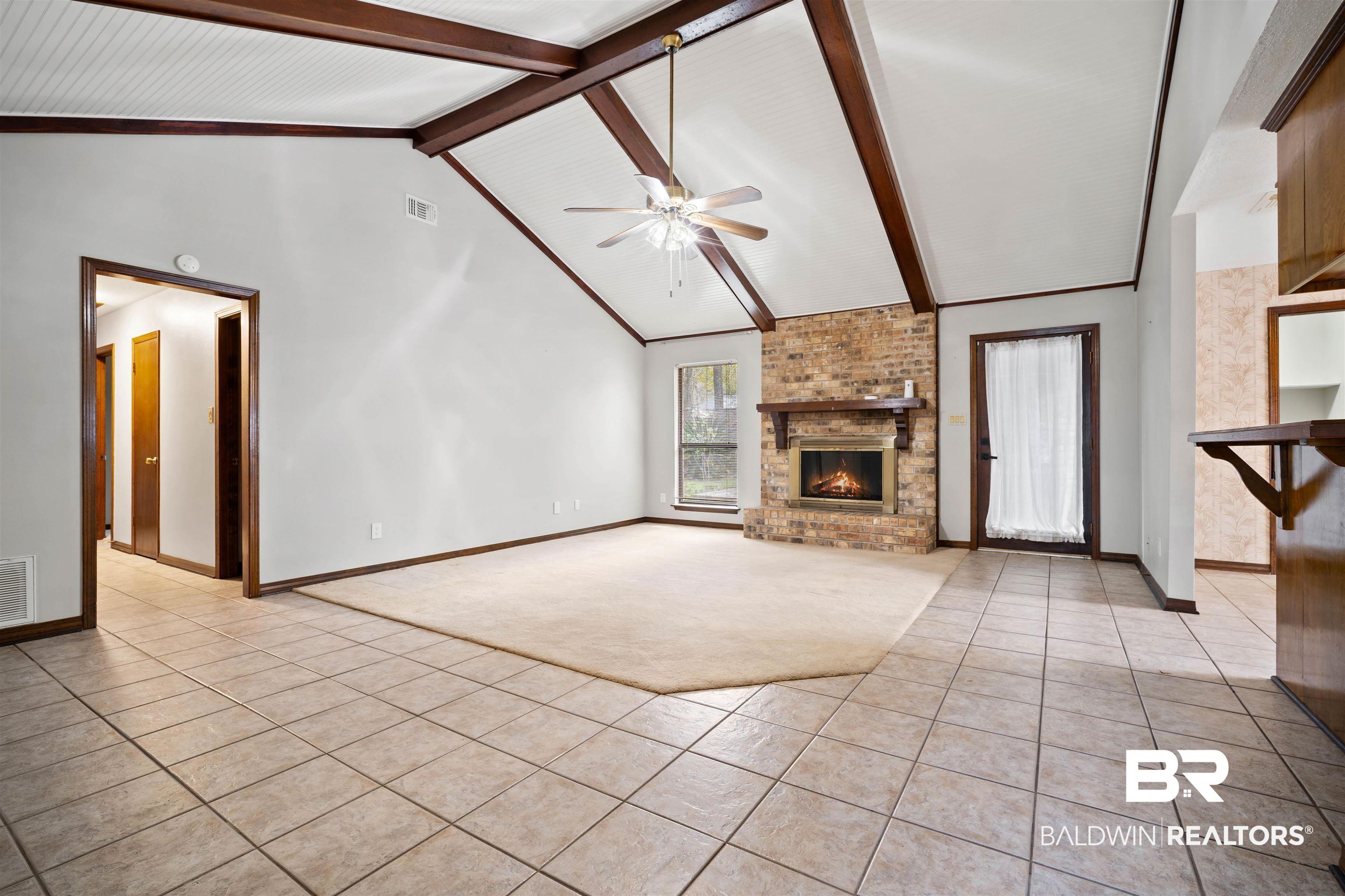 Image 2: Unfurnished living room featuring light tile patterned flooring, light carpet, a fireplace, and a ceiling fan