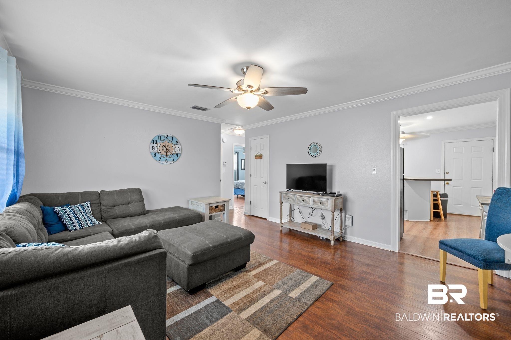 Image 2: Living room with visible vents, baseboards, a ceiling fan, crown molding, and wood finished floors