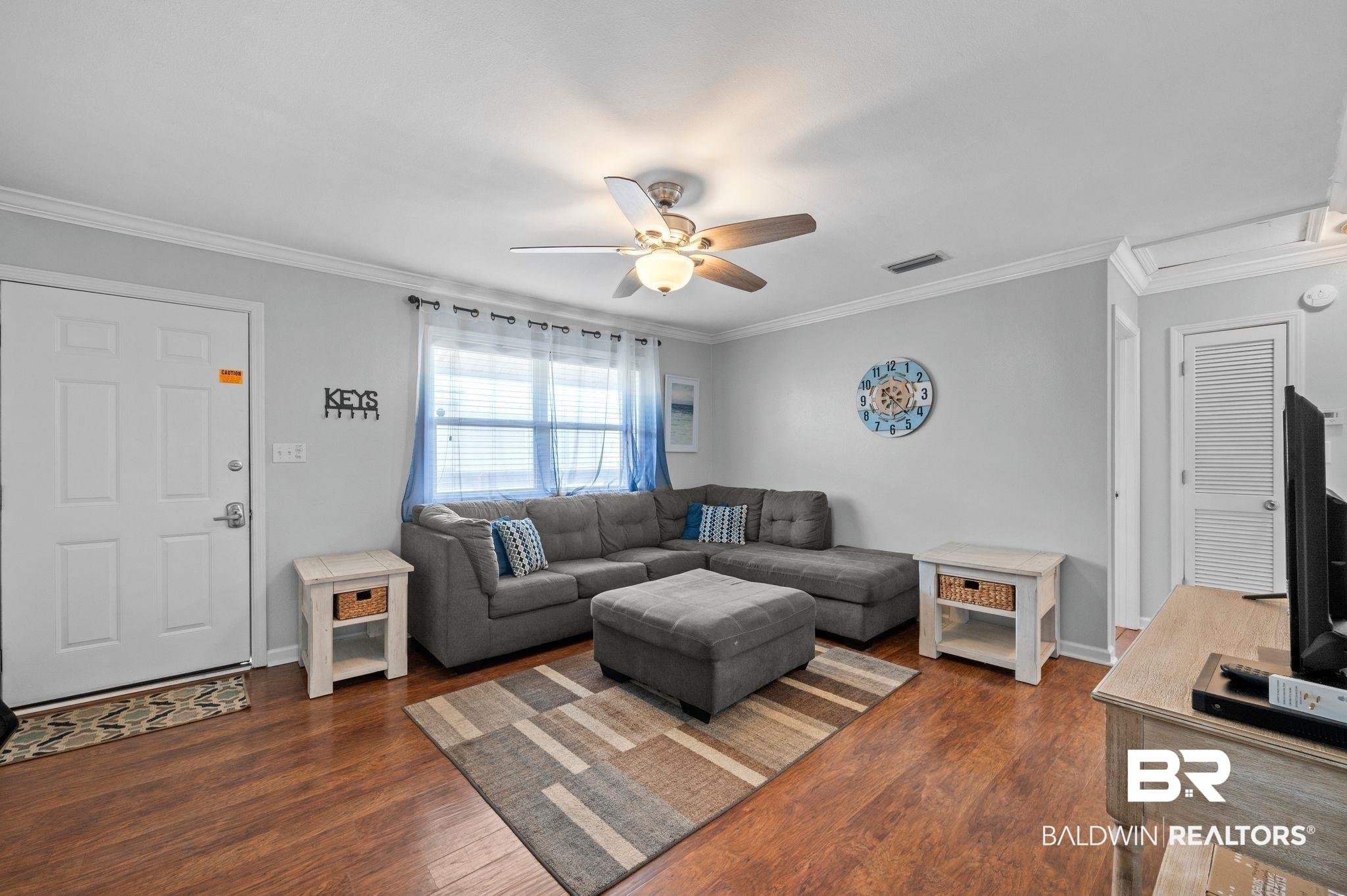 Image 3: Living area with dark wood-style floors, crown molding, a ceiling fan, and visible vents