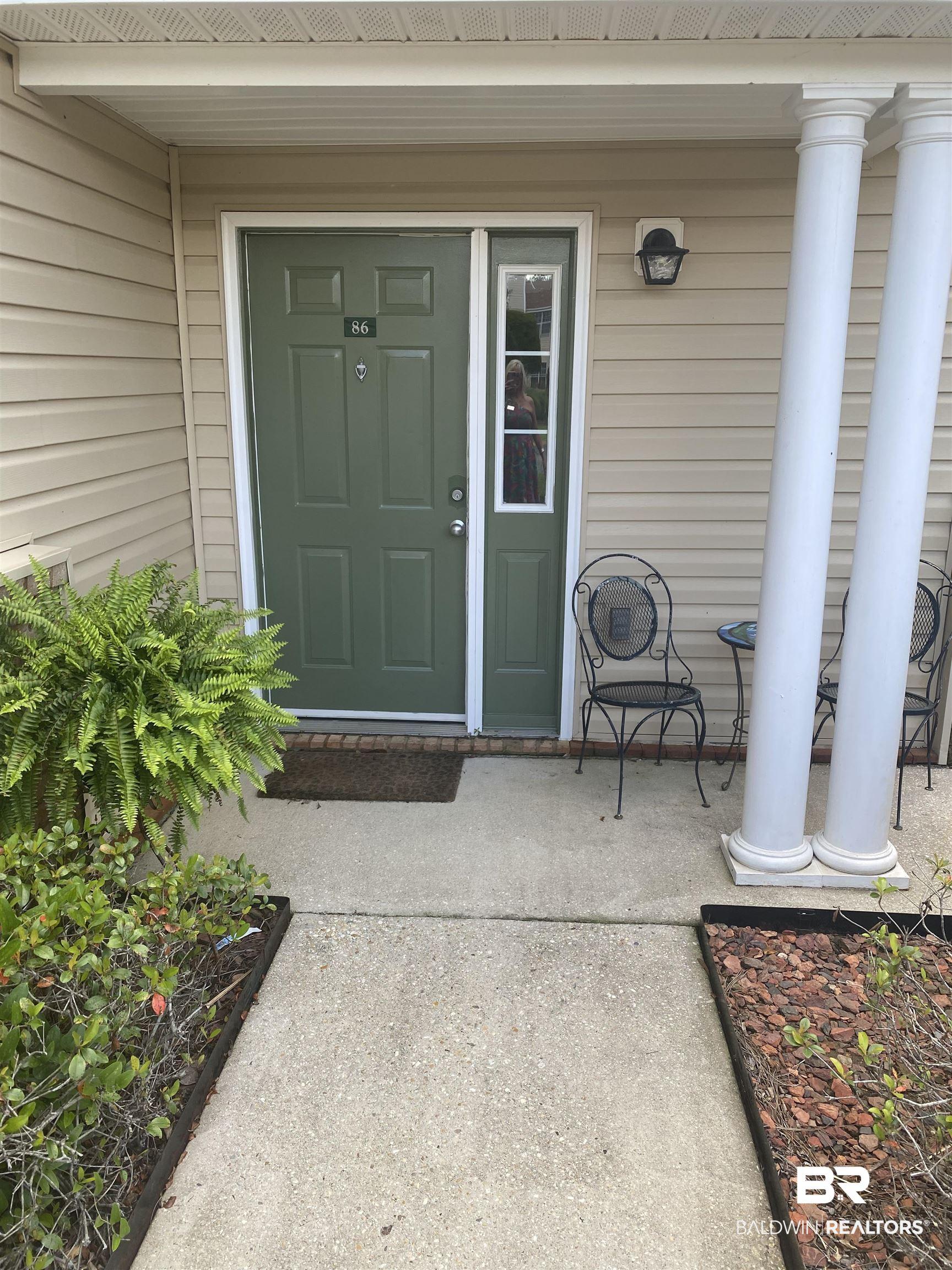 Image 2: Front entrance featuring a green paneled door with an adjacent sidelite, flanked by two decorative columns